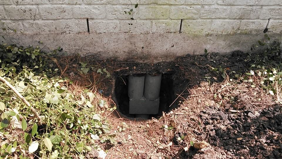 Concrete support blocks installed beneath a brick foundation